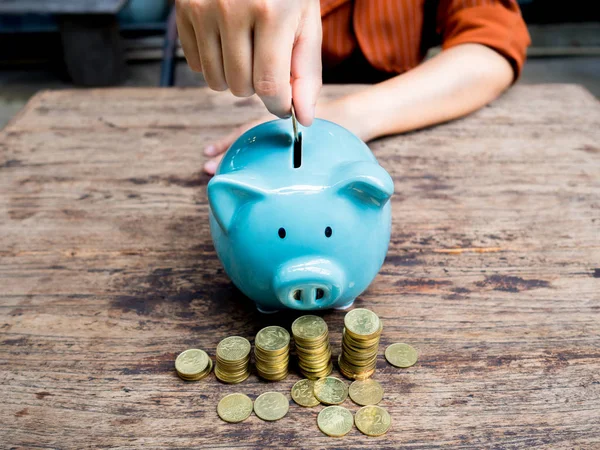 Business woman hand putting coin into blue piggy bank with gold coins pile growth graph, Saving money for future investment plan and retirement fund concept — Stock Photo, Image