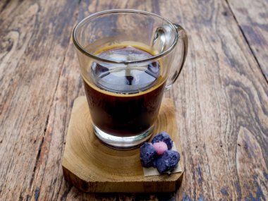 Ahşap masada bir fincan siyah kahve, tazelik vermeye hazır ve işadamı yanında