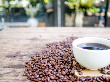 Bir fincan sade kahve ve kahve çekirdekleri ahşap masada, tazelik vermeye hazır ve işadamı yanında