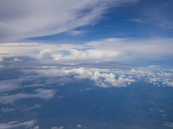 푸른 하늘 과높은 각도의 땅을 가진 비행기 창문에서 날아오는 구름 — 스톡 사진