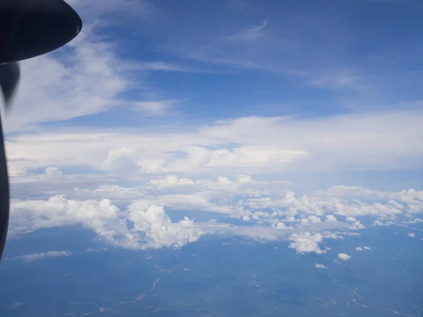 Nubes de la ventana del avión con cielo azul y suelo de ángulo alto — Foto de Stock