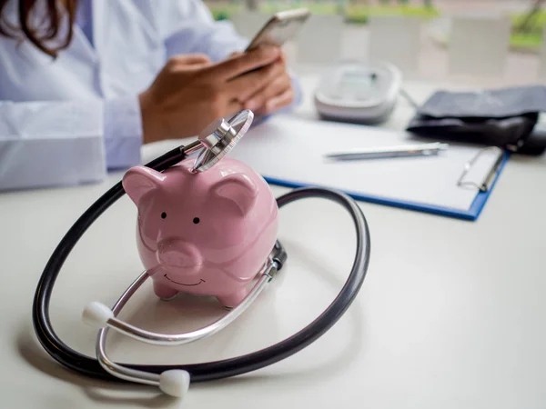 Růžová prasátko banka s lékařským stetoskopem a tlakoměrem, Šetřit peníze na budoucí plán a koncepce zdravotního pojištění — Stock fotografie