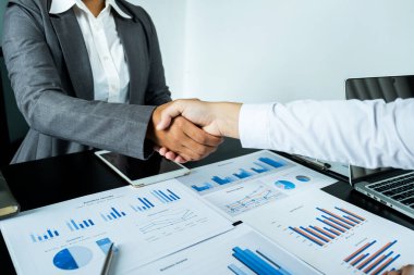 İş adamları ve iş kadınları iş gelirlerini artırmak için strateji planlamak için toplantı üstüne el ele tutuşuyorlar. Beyin fırtınası grafiği analizi yapın ve yeni hedefin başarısını tartışın..