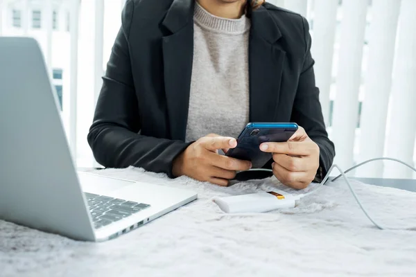 Business women charge mobile phones while sitting at a desk.