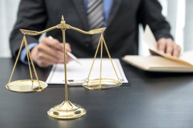 Erkek avukatın önünde duran adalet terazisi iş anlaşmazlığına danışma hizmeti sunuyor.