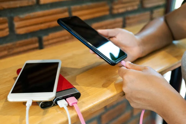 Akıllı telefon pili ve aygıt paylaşımını şarj ederken genç kadınların el ele tutuşması ve akıllı telefon oynaması.