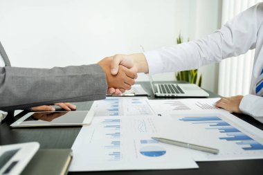 İş adamları ve iş kadınları iş gelirlerini artırmak için strateji planlamak için toplantı üstüne el ele tutuşuyorlar. Beyin fırtınası grafiği analizi yapın ve yeni hedefin başarısını tartışın..