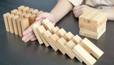 Kadın diğer tahta blokları korumak için ahşap blokları elle durdurur yönetim ve strateji planı riskini kavrar..