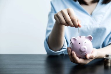 Kadın domuz kumbarasına para yatırıyor, işleri başarıya taşıyor, gelecek planı ve emeklilik fonu konsepti için para biriktiriyor..