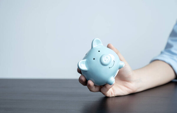 Woman hand holding piggy bank, step up start up business to success, Saving money for future plan and retirement fund concept.