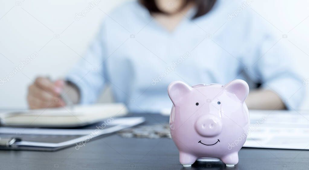 piggy bank on the table and young woman checks to account, step up start-up business to success, Saving money for future plan and retirement fund concept.