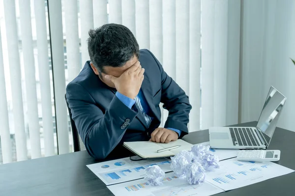 Businessman acted with tired stress anxiety from the frustrated business crisis, paperwork paper cube mess chaos on the table.