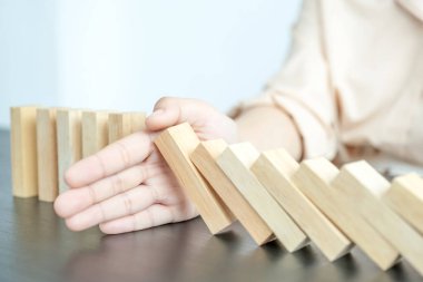 Kadın diğer tahta blokları korumak için ahşap blokları elle durdurur yönetim ve strateji planı riskini kavrar..