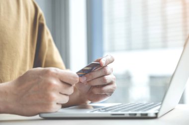İş adamının elinde bilgisayardan online alışveriş için kredi kartı var. Ev bilgisayarı, ödeme e-ticaret, internet bankacılığı, harcama parası..