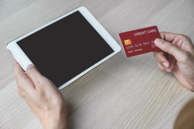 İş adamının elinde evden alınan bilgisayar tabletinden online alışveriş için kredi kartı, ödeme e-ticaret, internet bankacılığı, harcama parası.