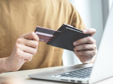 İş adamının elinde bilgisayardan online alışveriş için kredi kartı var. Ev bilgisayarı, ödeme e-ticaret, internet bankacılığı, harcama parası..