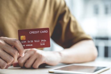 İş adamının elinde evden alınan bilgisayar tabletinden online alışveriş için kredi kartı, ödeme e-ticaret, internet bankacılığı, harcama parası.