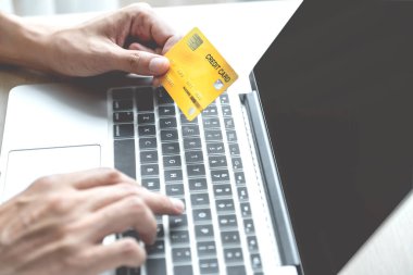 İş adamının elinde bilgisayardan online alışveriş için kredi kartı var. Ev bilgisayarı, ödeme e-ticaret, internet bankacılığı, harcama parası..