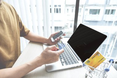 İş adamının elinde bilgisayardan online alışveriş için kredi kartı var. Ev bilgisayarı, ödeme e-ticaret, internet bankacılığı, harcama parası..