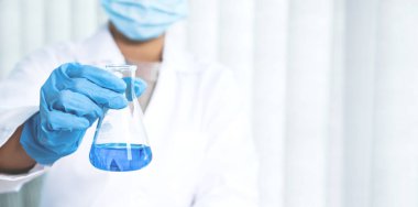 Bilim adamları laboratuarda araştırma ve analiz için mavi kimyasal sıvıyla dolu cam bir tüp tutuyorlar..