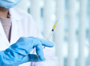 Doktorlar şırıngayı, aşıyı, virüsü, bakteriyi ve sarı kimyasal sıvıyı laboratuvarda tutuyorlar..