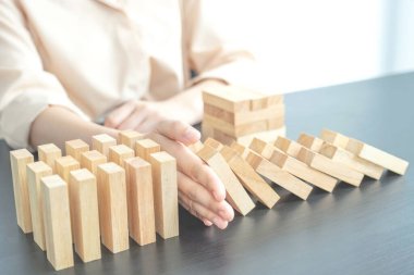 Kadın diğer tahta blokları korumak için ahşap blokları elle durdurur yönetim ve strateji planı riskini kavrar..