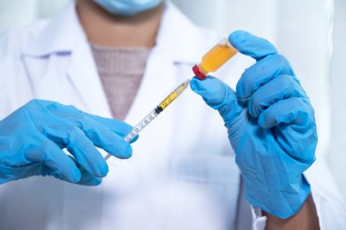 Doktorlar şırıngayı, aşıyı, virüsü, bakteriyi ve sarı kimyasal sıvıyı laboratuvarda tutuyorlar..