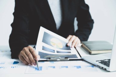 İş kadını, iş hedeflerini belirlemek ve yeni hedefe ulaşmayı planlamak için ofisteki grafiği bilgisayarla analiz ediyor..