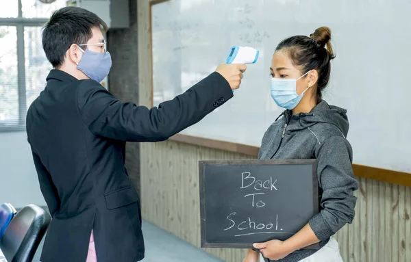 Professor fever check young woman before going to class. Open university first health checks up measurement as epidemic prevention covid19 back to school concept.