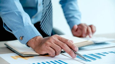 İşadamı, iş hedeflerini belirlemek ve yeni hedefe ulaşmayı planlamak için ofisteki bilgisayarı kullanarak grafiği analiz ediyor..