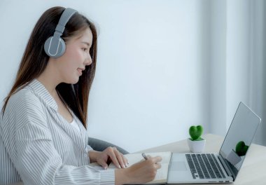 Genç kız öğrenci dizüstü bilgisayar dersi izlerken not alıyor online sınıf video konferansı eğitimi evden yeniden öğreniyor.