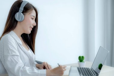 Genç kız öğrenci dizüstü bilgisayar dersi izlerken not alıyor online sınıf video konferansı eğitimi evden yeniden öğreniyor.