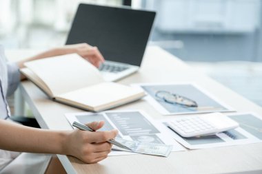 İş kadını, iş hedeflerini belirlemek ve yeni hedefe ulaşmayı planlamak için ofisteki grafiği bilgisayarla analiz ediyor..