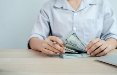 İş kadınları muhasebecisi elleri dolar sayar ve çalışma odasındaki beyaz masanın üzerindeki vergiyi hesaplar..