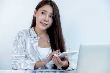 İş kadını elinde tablet tutuyor ve iş hedefleri belirlemek ve yeni hedefe ulaşmayı planlamak için ofisteki dizüstü bilgisayarla çizelgeyi analiz ediyor..