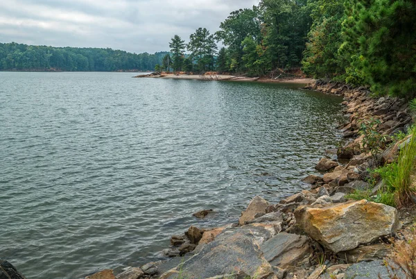 Lake shoreline with rocks and trees — Stock Photo, Image