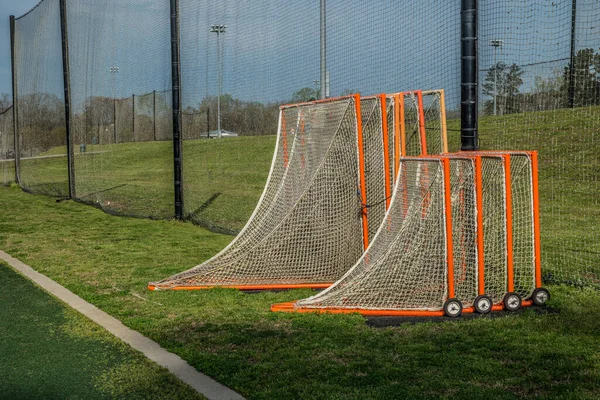 Stacked together different sizes of soccer goal nets set aside when not in use at a sports field on a sunny day in spring