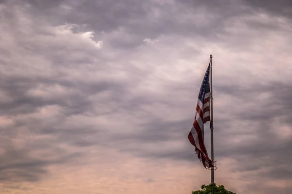 朝の空を背景に嵐の雲や鳥が飛び交う風に誇らしげに舞う大きなアメリカ国旗 — ストック写真