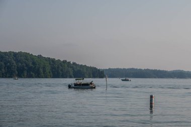 Sıcak ve sisli bir günde, yazın güneşli bir öğleden sonra balığa çıkan ve hızla geçen insanlarla dolu bir sürü tekne aktivitesi.