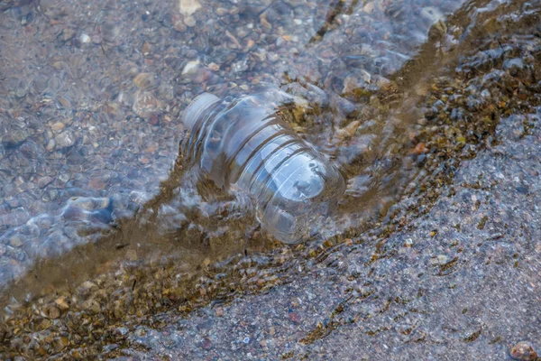 現在の岩礁の海岸に漂着し環境を汚染している廃棄物の捨てられたペットボトルごみ — ストック写真