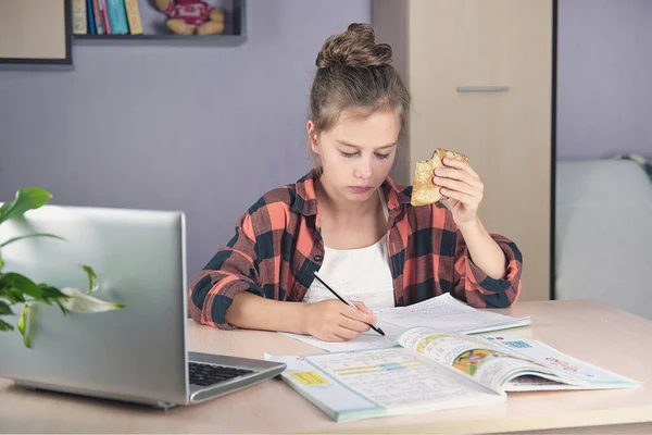Niño en casa en la mesa, haciendo los deberes y comiendo panqueques — Foto de Stock