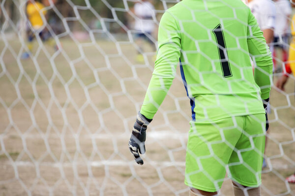 Goalkeeper stands against goal with net and stadium. Football ga