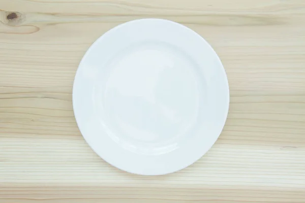 木製のテーブルの上に空の白いセラミックプレート — ストック写真