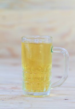 Ahşap bir arka plan üzerine yerleştirilen bir bardağa soğuk bira.