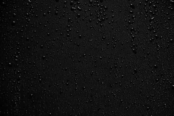 Vatten droppar på svart bakgrund och konsistens. — Stockfoto