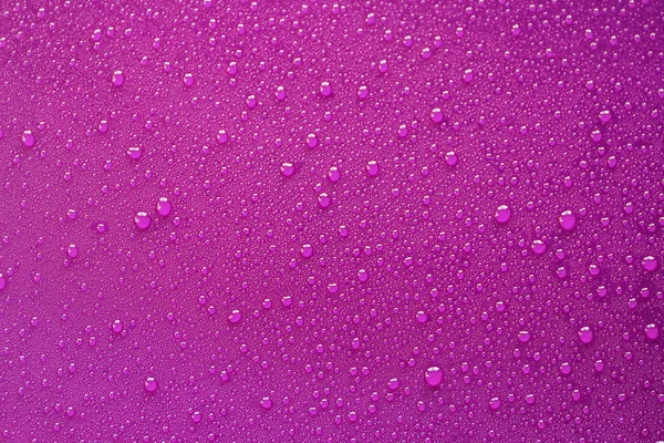 Gotas de agua sobre fondo púrpura . — Foto de Stock