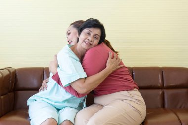 Hastanedeki hasta Asyalı anne kızına neşeyle sarılıyordu..