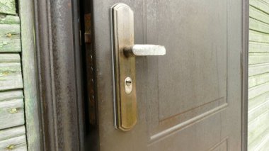 Kapı kolu hafif açık olan demir bir kapı.