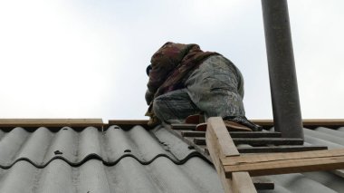 Erkek bir inşaat işçisi çatıda çalışıyor.