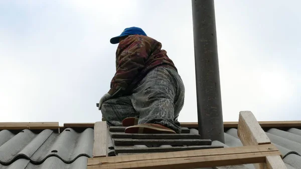 a male construction worker works on the roof